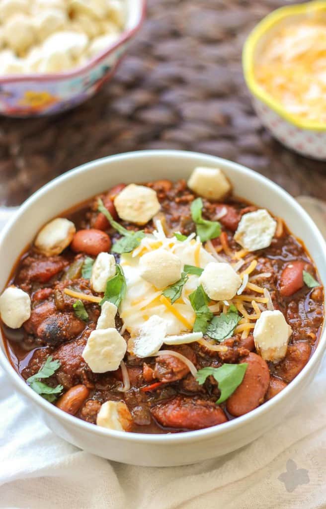 Chorizo Chili with Jalapeño Cornbread Waffles is perfect for game day, a chilly fall night or neighborhood potluck. This beefy flavored packed chili gets a slight kick from the spicy chorizo sausage. Served on top of cornbread waffles, dolloped with cheese and cilantro, and you've got yourself a well rounded meal! | Strawberry Blondie Kitchen