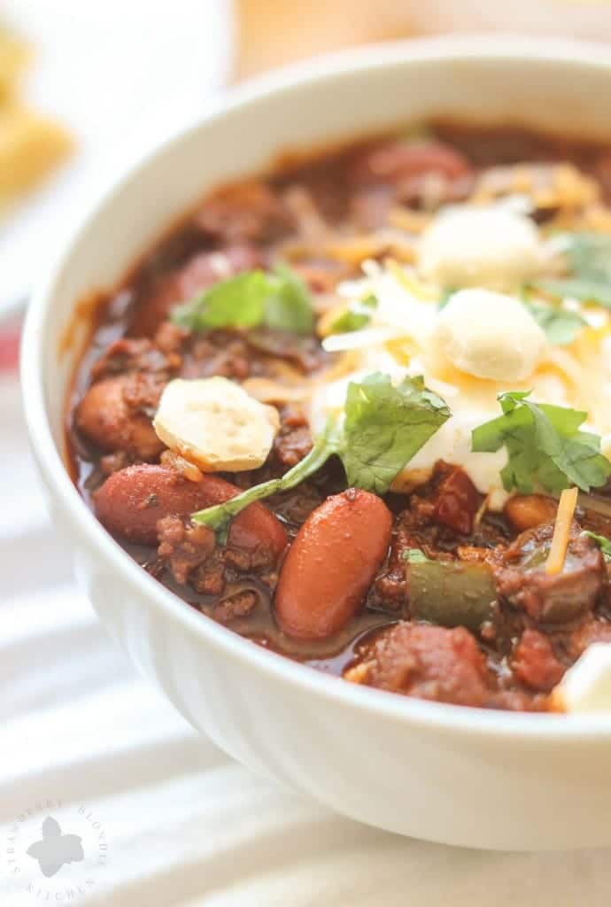 Chorizo Chili with Jalapeño Cornbread Waffles is perfect for game day, a chilly fall night or neighborhood potluck. This beefy flavored packed chili gets a slight kick from the spicy chorizo sausage. Served on top of cornbread waffles, dolloped with cheese and cilantro, and you've got yourself a well rounded meal! | Strawberry Blondie Kitchen