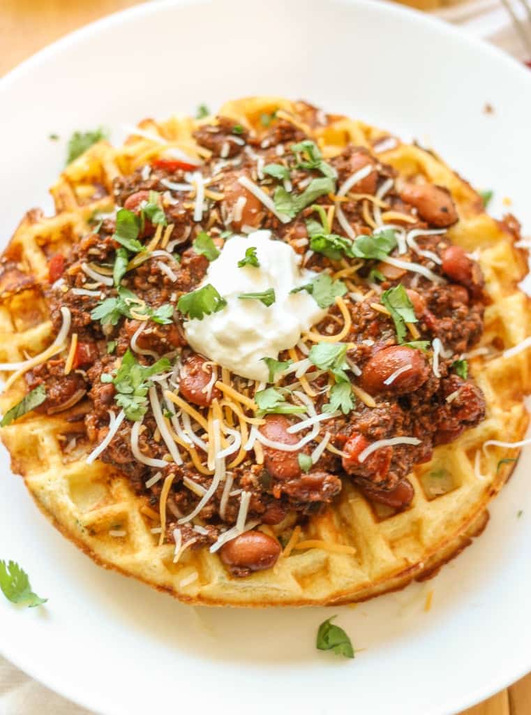 Chorizo Chili with Jalapeño Cornbread Waffles is perfect for game day, a chilly fall night or neighborhood potluck. This beefy flavored packed chili gets a slight kick from the spicy chorizo sausage. Served on top of cornbread waffles, dolloped with cheese and cilantro, and you've got yourself a well rounded meal! | Strawberry Blondie Kitchen