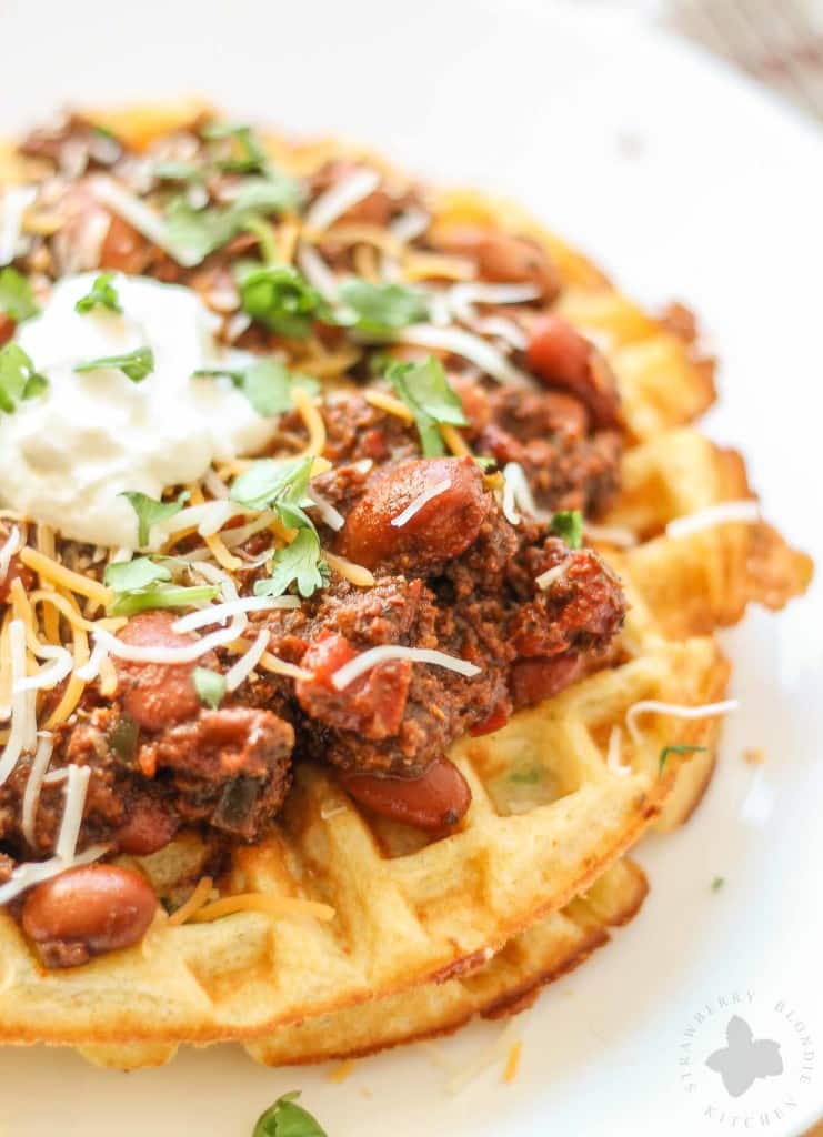 Chorizo Chili with Jalapeño Cornbread Waffles is perfect for game day, a chilly fall night or neighborhood potluck. This beefy flavored packed chili gets a slight kick from the spicy chorizo sausage. Served on top of cornbread waffles, dolloped with cheese and cilantro, and you've got yourself a well rounded meal! | Strawberry Blondie Kitchen