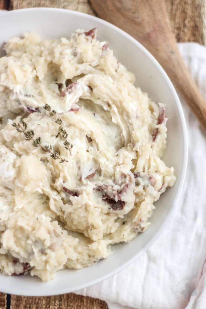 Free up space in your oven this holiday season with these Slow Cooker Goat Cheese Mashed Potatoes. They're tangy and full of garlic flavor from the herb goat cheese, fluffy and irresistibly delicious. They're sure to have your guests going back for seconds! | Strawberry Blondie Kitchen