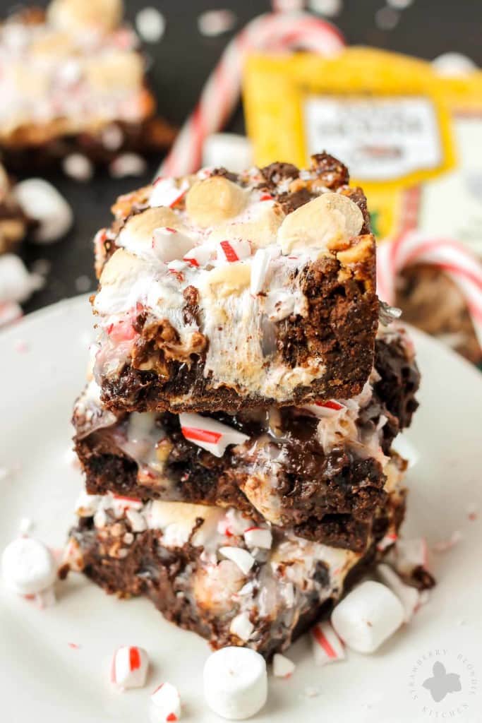 Have your hot cocoa and eat it too with these Peppermint Hot Cocoa Cookie Bars. They feature 7 layers of delicious cookies, chocolate, peanuts, coconuts, marshmallows and peppermint and then drizzled with sweetened condensed milk | Strawberry Blondie Kitchen