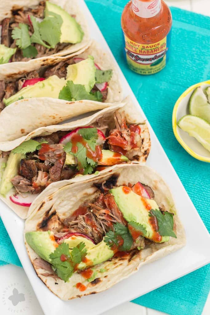 Tender, spicy, moist and juicy these Slow Cooker Spicy Pork Carnitas are perfect for the BIG GAME! Place on top of a tortilla with fresh ingredients, piled high on nachos or sandwiched between bread, no matter how you serve them, you've got a crowd pleaser perfect for game day, dinner or a fiesta! | Strawberry Blondie Kitchen