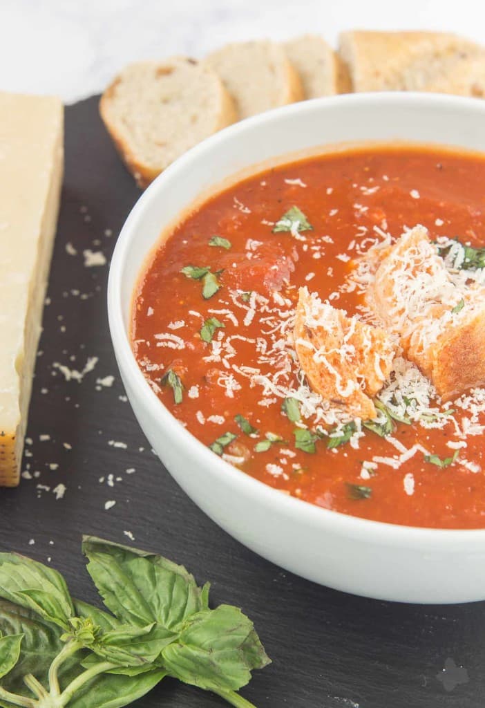 Garden vegetables are roasted to perfection and then placed in the slow cooker to simmer until tender making this Slow Cooker Roasted Red Pepper and Tomato Soup delicious and comforting. Top with freshly grated parmesan cheese and basil and serve a chunk of hearty bread on the side for the perfect weeknight dinner. | Strawberry Blondie Kitchen