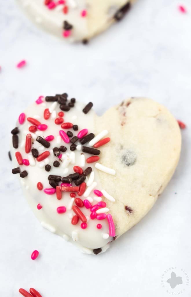 Surprise and delight your Valentine with these White Chocolate Cranberry Shortbread Heart Cookies. Nothing says I love you more than fresh home baked cookies shaped like hearts, dipped in white chocolate and covered in sprinkles!