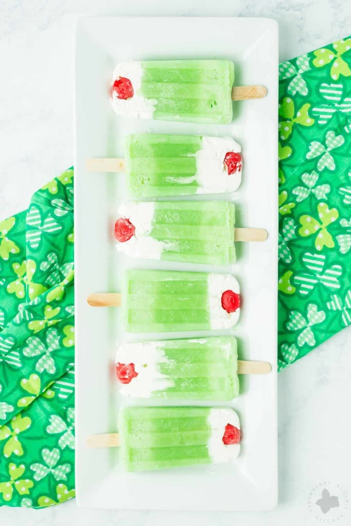 The classic Shamrock Shake you know and love turned Popsicle. Cool, creamy mint flavored frozen yogurt popsicles complete with whipped cream and a cherry on top! | Strawberry Blondie Kitchen