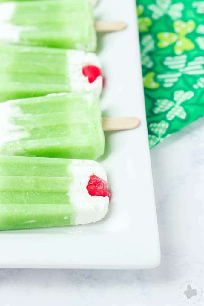 The classic Shamrock Shake you know and love turned Popsicle. Cool, creamy mint flavored frozen yogurt popsicles complete with whipped cream and a cherry on top! | Strawberry Blondie Kitchen