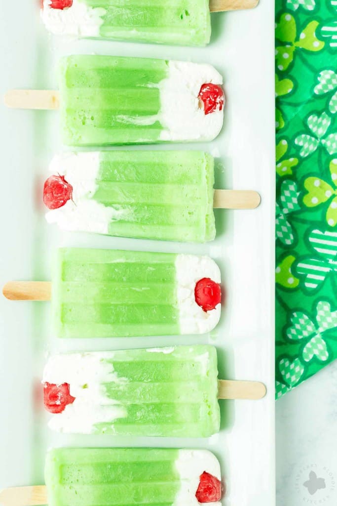 The classic Shamrock Shake you know and love turned Popsicle. Cool, creamy mint flavored frozen yogurt popsicles complete with whipped cream and a cherry on top! | Strawberry Blondie Kitchen