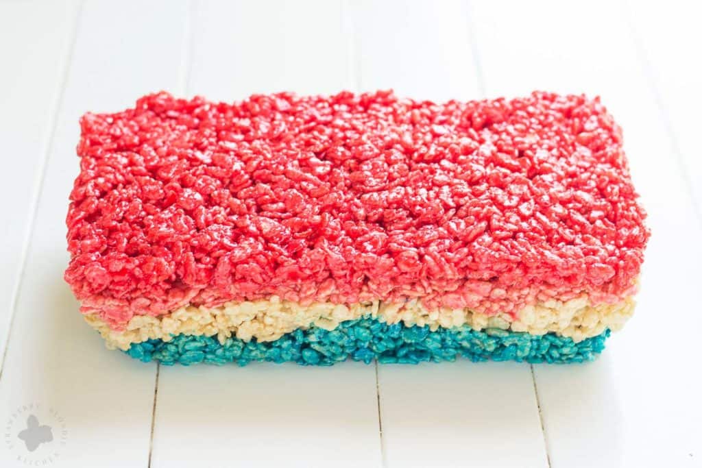 Reminiscent of the classic bomb pop, with much less mess, these Patriotic Crispy Treats are not your ordinary dessert. They’re layers of flavors with strawberry, vanilla and blue raspberry. A fun, new and Patriotic twist on everyone's favorite past time treat. Perfect addition to your next American party! | Strawberry Blondie Kitchen