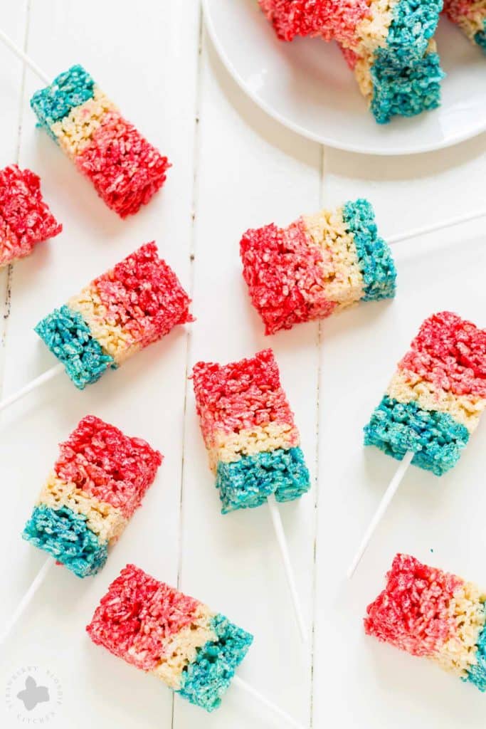 Reminiscent of the classic bomb pop, with much less mess, these Patriotic Crispy Treats are not your ordinary dessert. They’re layers of flavors with strawberry, vanilla and blue raspberry. A fun, new and Patriotic twist on everyone's favorite past time treat. Perfect addition to your next American party! | Strawberry Blondie Kitchen