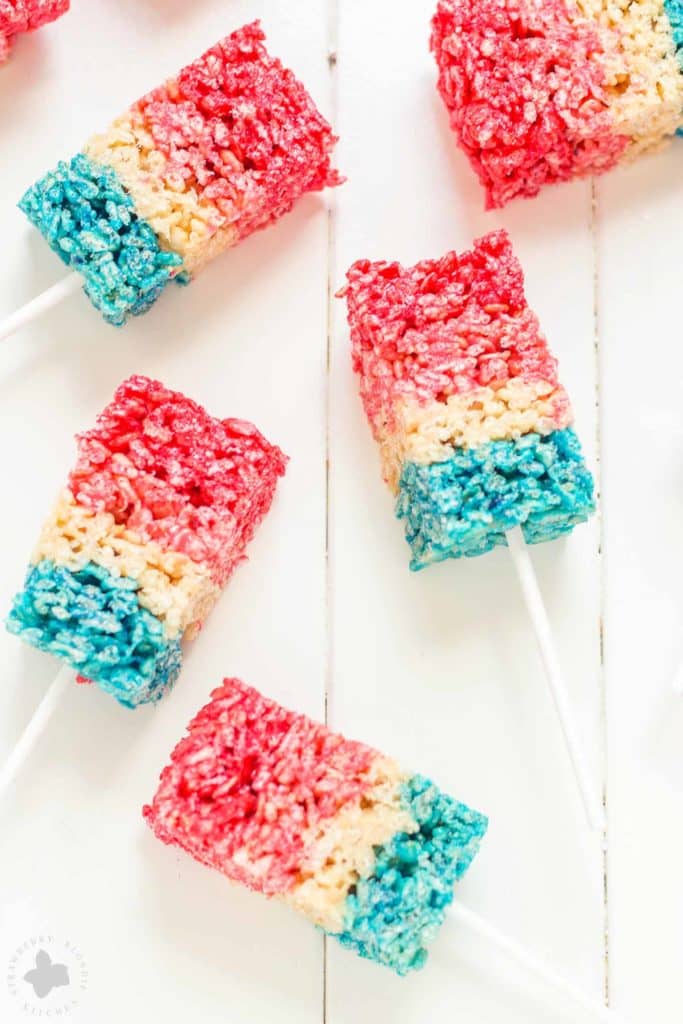 Reminiscent of the classic bomb pop, with much less mess, these Patriotic Crispy Treats are not your ordinary dessert. They’re layers of flavors with strawberry, vanilla and blue raspberry. A fun, new and Patriotic twist on everyone's favorite past time treat. Perfect addition to your next American party! | Strawberry Blondie Kitchen