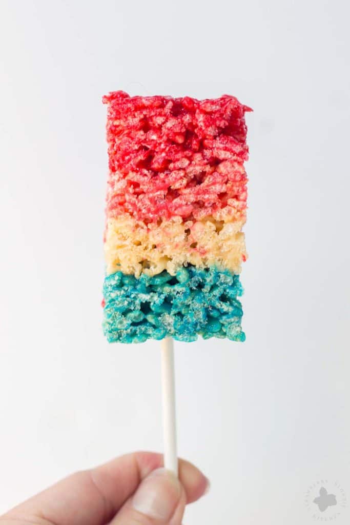 Reminiscent of the classic bomb pop, with much less mess, these Patriotic Crispy Treats are not your ordinary dessert. They’re layers of flavors with strawberry, vanilla and blue raspberry. A fun, new and Patriotic twist on everyone's favorite past time treat. Perfect addition to your next American party! | Strawberry Blondie Kitchen