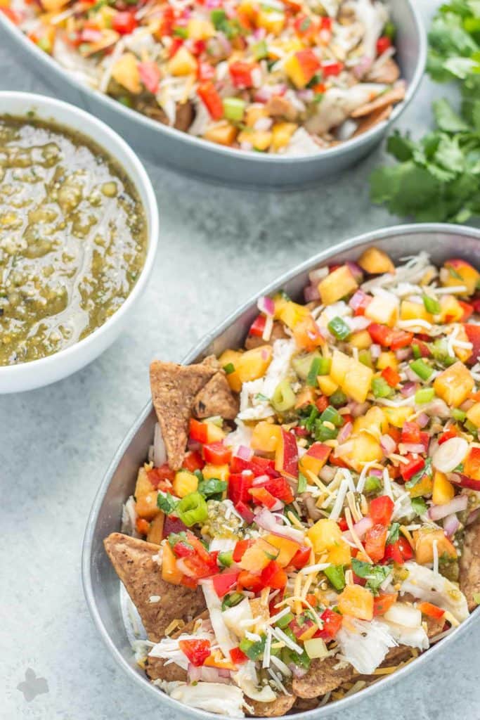 Chicken Nachos with Peach Salsa are bursting with bright summer flavors. Featuring juicy, ripe peaches, fresh chopped veggies and herbs, perfectly cooked chicken and a homemade tomatillo sauce, these nachos will have skipping the taco stand! | Strawberry Blondie Kitchen