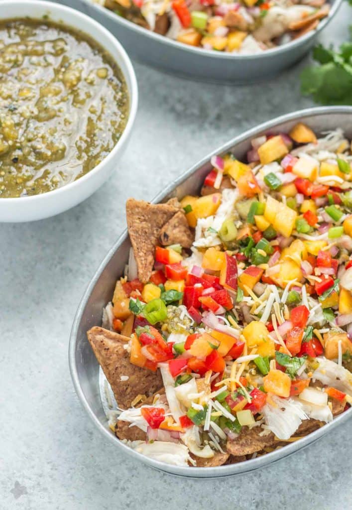 Chicken Nachos with Peach Salsa are bursting with bright summer flavors. Featuring juicy, ripe peaches, fresh chopped veggies and herbs, perfectly cooked chicken and a homemade tomatillo sauce, these nachos will have skipping the taco stand! | Strawberry Blondie Kitchen