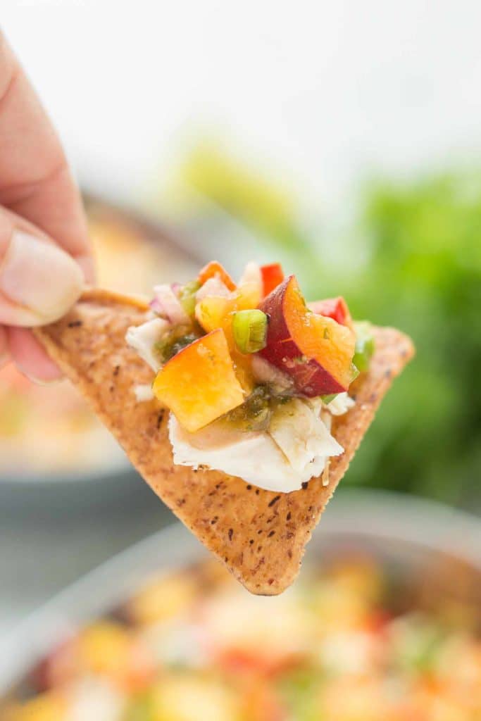 Chicken Nachos with Peach Salsa are bursting with bright summer flavors. Featuring juicy, ripe peaches, fresh chopped veggies and herbs, perfectly cooked chicken and a homemade tomatillo sauce, these nachos will have skipping the taco stand! | Strawberry Blondie Kitchen