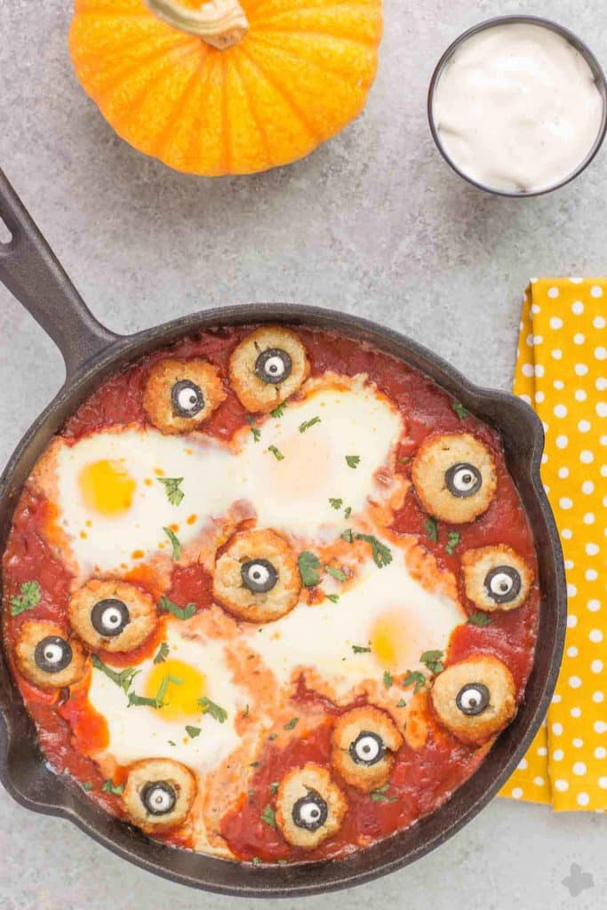 Eggs are baked in a tomato sauce and then breaded mushrooms with sliced black olives, made to looks like eyes, are nestled alongside to create this Halloween Eyeball Skillet. A festive meal sure to please the entire family! | Strawberry Blondie Kitchen