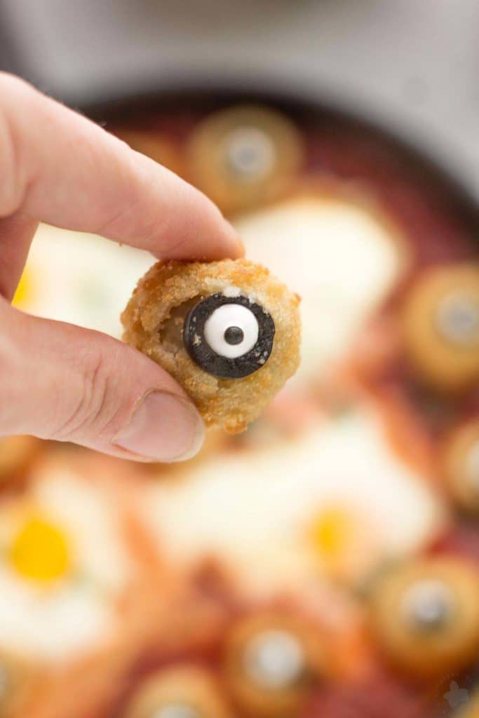 Eggs are baked in a tomato sauce and then breaded mushrooms with sliced black olives, made to looks like eyes, are nestled alongside to create this Halloween Eyeball Skillet. A festive meal sure to please the entire family! | Strawberry Blondie Kitchen