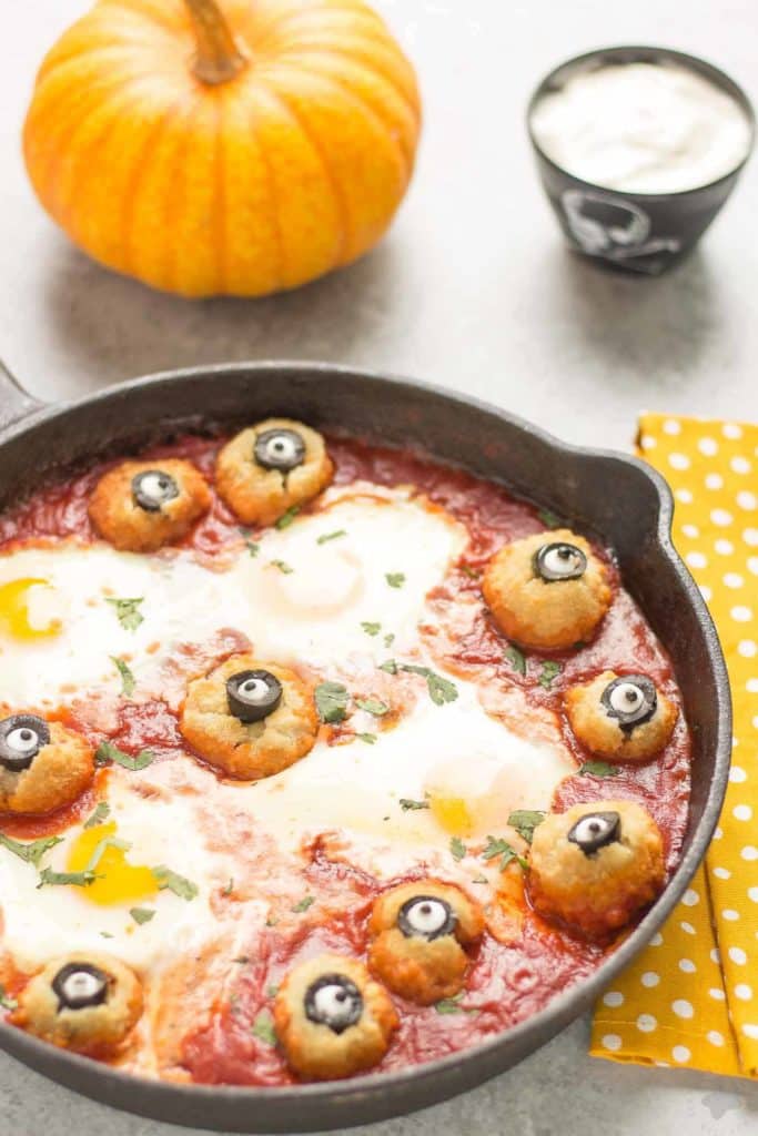 Eggs are baked in a tomato sauce and then breaded mushrooms with sliced black olives, made to looks like eyes, are nestled alongside to create this Halloween Eyeball Skillet. A festive meal sure to please the entire family! | Strawberry Blondie Kitchen