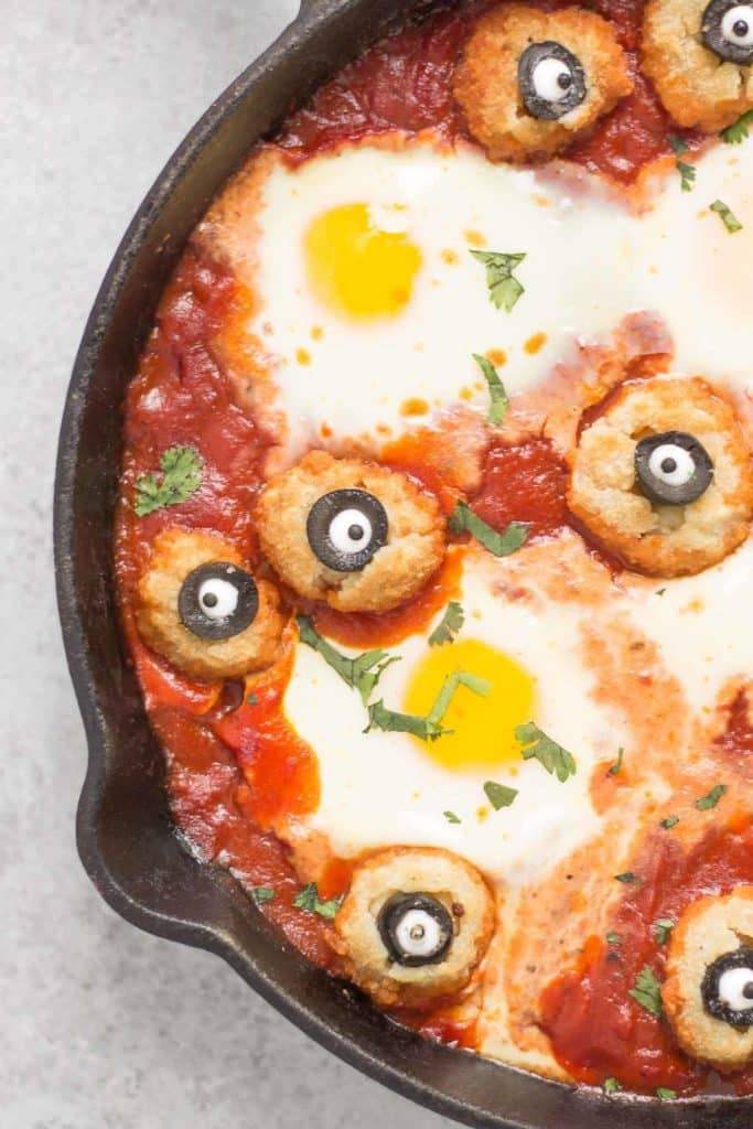 Eggs are baked in a tomato sauce and then breaded mushrooms with sliced black olives, made to looks like eyes, are nestled alongside to create this Halloween Eyeball Skillet. A festive meal sure to please the entire family! | Strawberry Blondie Kitchen