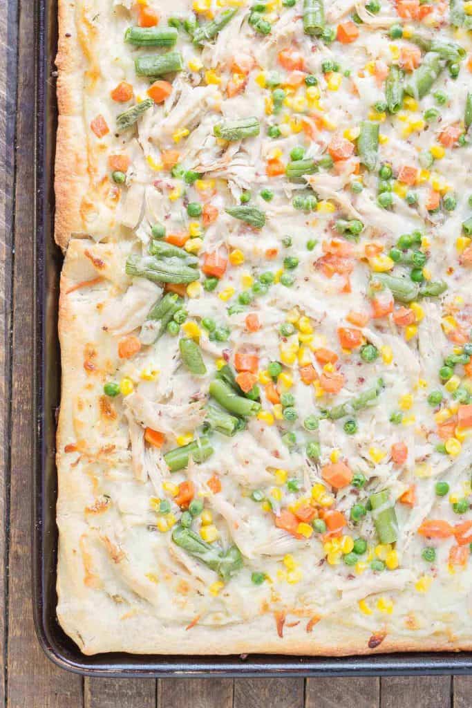 No one will be able to say no to Leftover Turkey Pot Pie Slab Pizza. Filled with extra cheese, vegetables and turkey, this pizza tastes exactly like a delicious pot pie! Perfect for game day, feeding a crowd and using up Thanksgiving leftovers! | Strawberry Blondie Kitchen