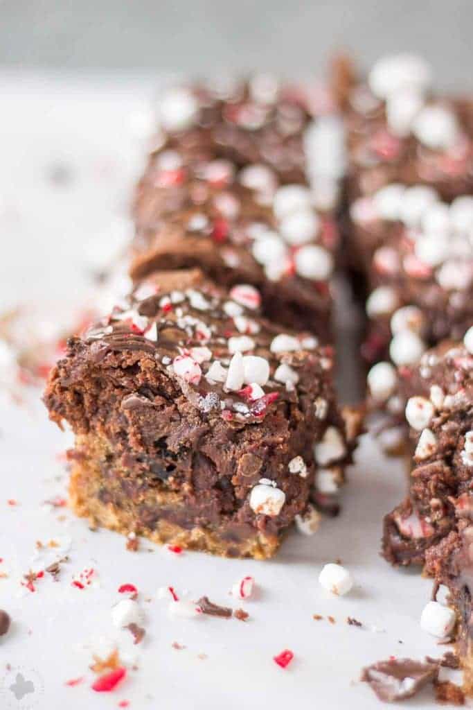 These Peppermint Hot Chocolate Brookies feature a layer of chocolate chip cookies, peppermint sandwich cookies, a layer of brownies and then topped with dark chocolate, crushed peppermint and mini marshmallows. | Strawberry Blondie Kitchen