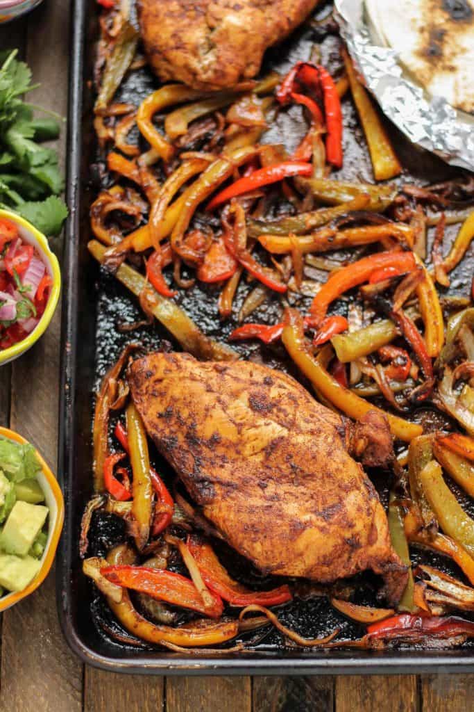 Bursting with flavor and cooked all on ONE pan, these easy Sheet Pan Chicken Fajitas are sure to become permanent in your dinner rotation. You'll love the quick cleanup too! | Strawberry Blondie Kitchen