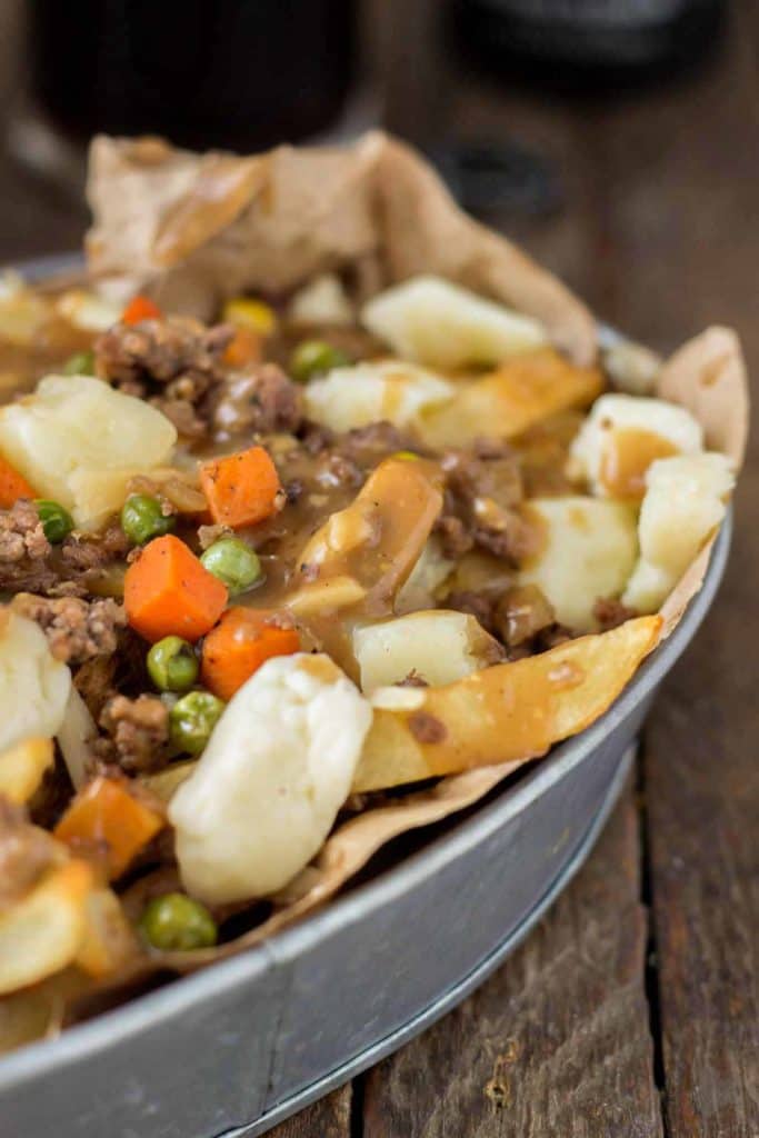 Crispy fries piled high with beef and mixed vegetables, smothered in Guinness gravy and topped with cheese curds make for one awesome Shepherd's Pie Poutine. | Strawberry Blondie Kitchen