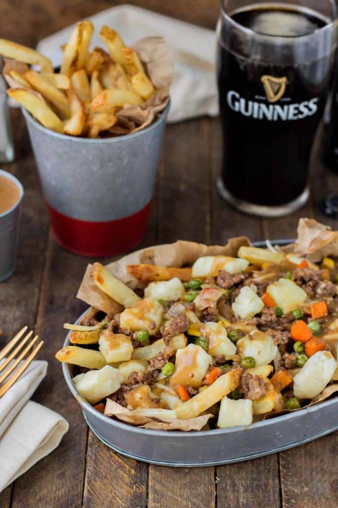 Crispy fries piled high with beef and mixed vegetables, smothered in Guinness gravy and topped with cheese curds make for one awesome Shepherd's Pie Poutine. | Strawberry Blondie Kitchen
