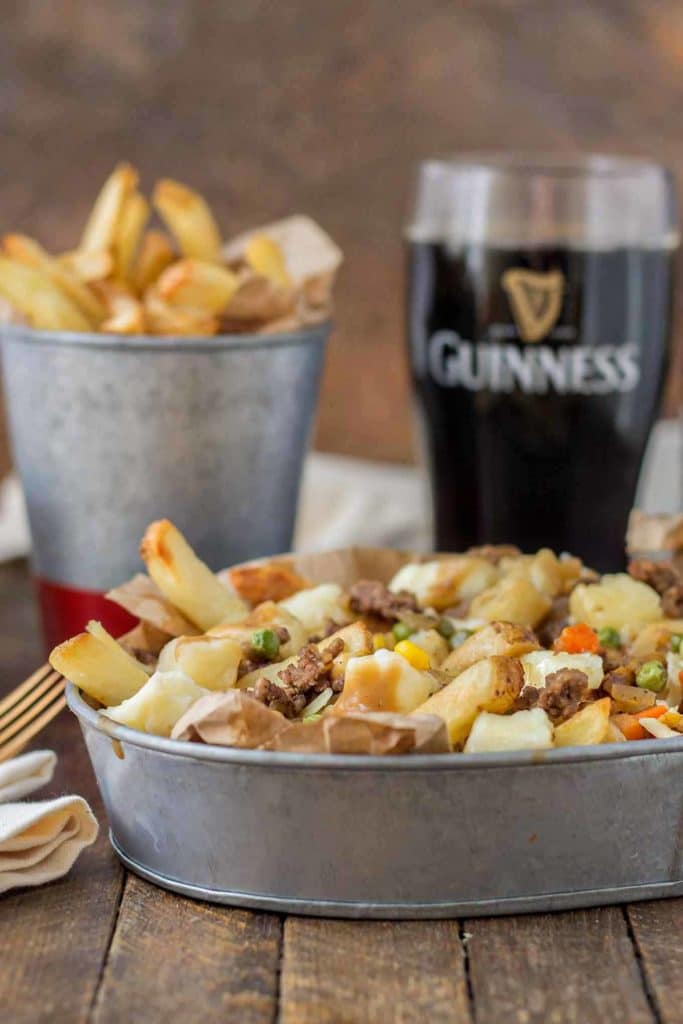 Crispy fries piled high with beef and mixed vegetables, smothered in Guinness gravy and topped with cheese curds make for one awesome Shepherd's Pie Poutine. | Strawberry Blondie Kitchen