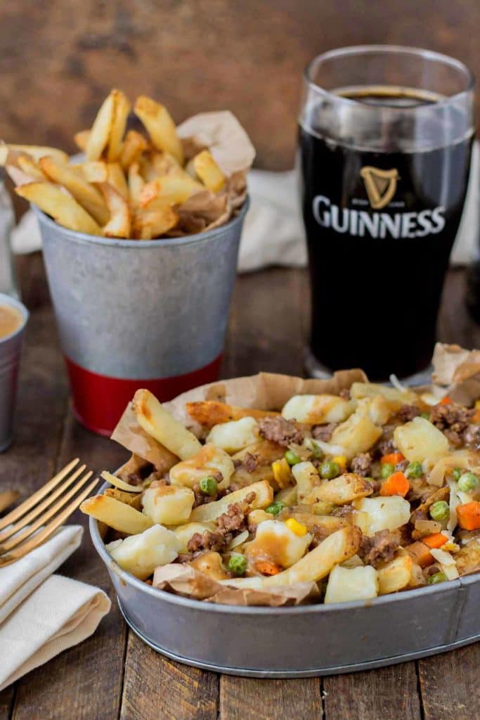 Crispy fries piled high with beef and mixed vegetables, smothered in Guinness gravy and topped with cheese curds make for one awesome Shepherd's Pie Poutine. | Strawberry Blondie Kitchen