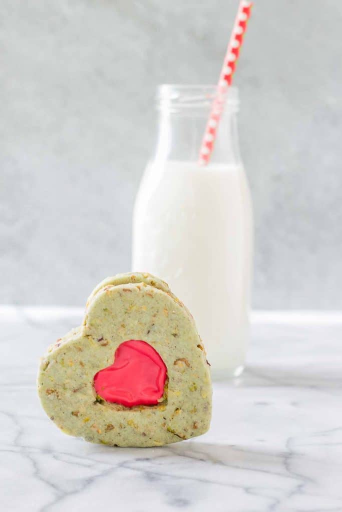 Your heart will grow three sizes with one bite of these Grinch Sandwich Cookies.  Pistachio shortbread cookies, with heart cutouts and red icing pay homage to one of childhood's favorite movies. | Strawberry Blondie Kitchen