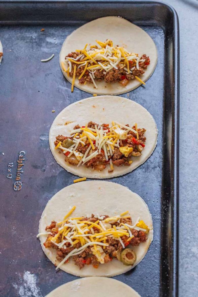 Place 1-2 tablespoons of empanada filling onto one side of the dough.  Top with cheese.