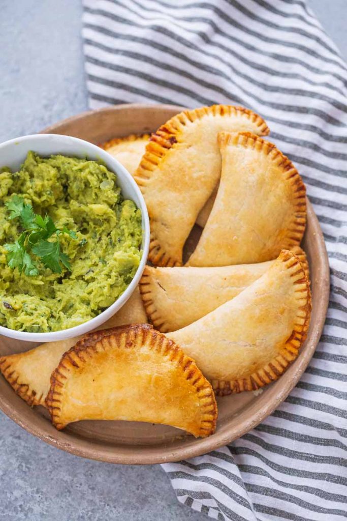 baked beef empanadas on a tray with guacamole