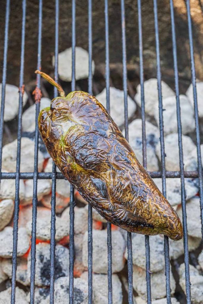 Poblano pepper chars on a charcoal grill