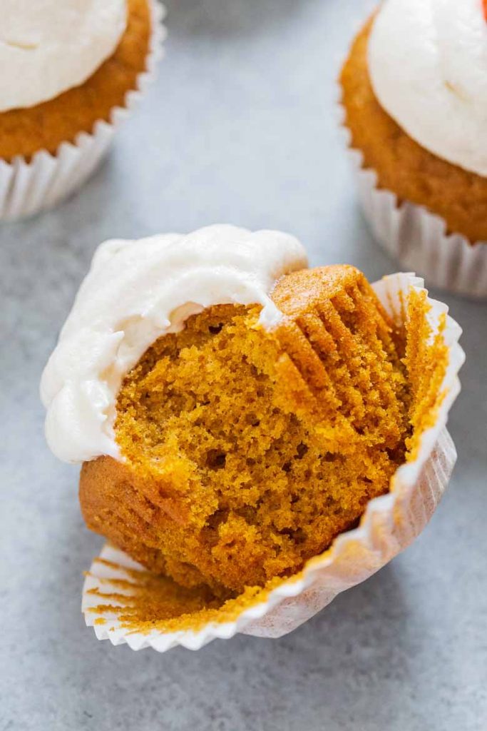 A bite taken out of Pumpkin Cupcakes with Marshmallow Frosting