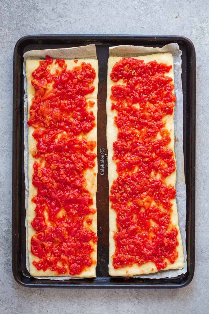 Place crushed tomatoes on top of cooked pizza crust