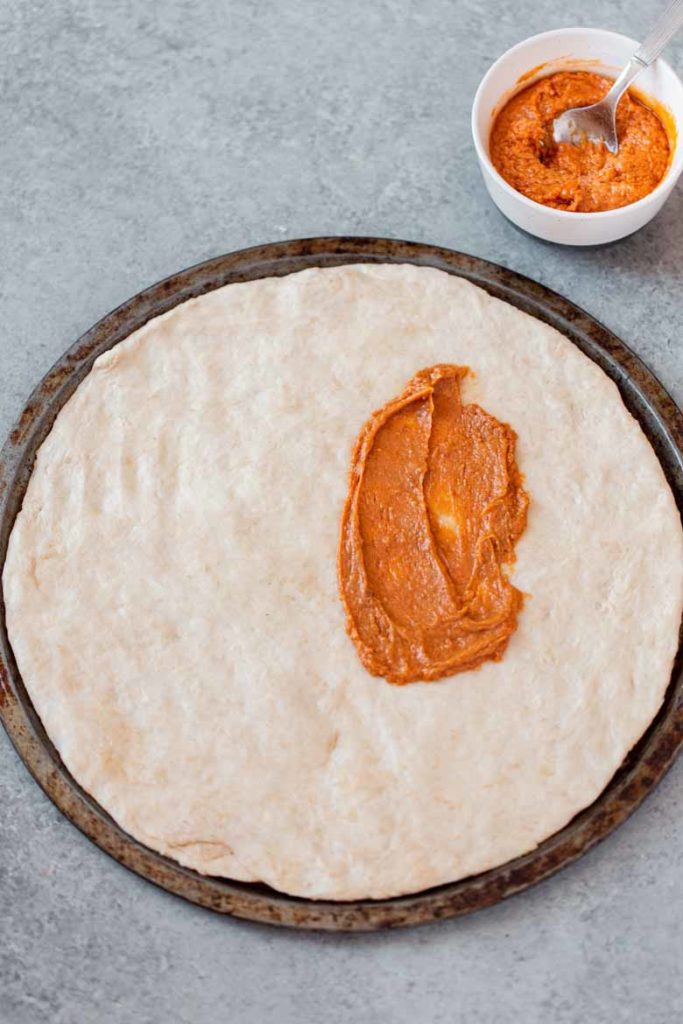 Spread homemade peanut sauce onto pizza crust