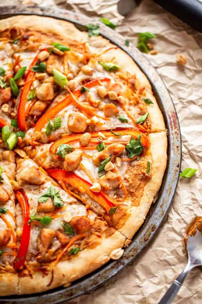 Thai Chicken Pizza cut up on a pizza pan
