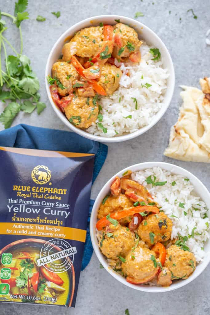 two bowls of chicken tikka masala meatballs with jasmine rice alongside Blue Elephant Yellow Curry Sauce