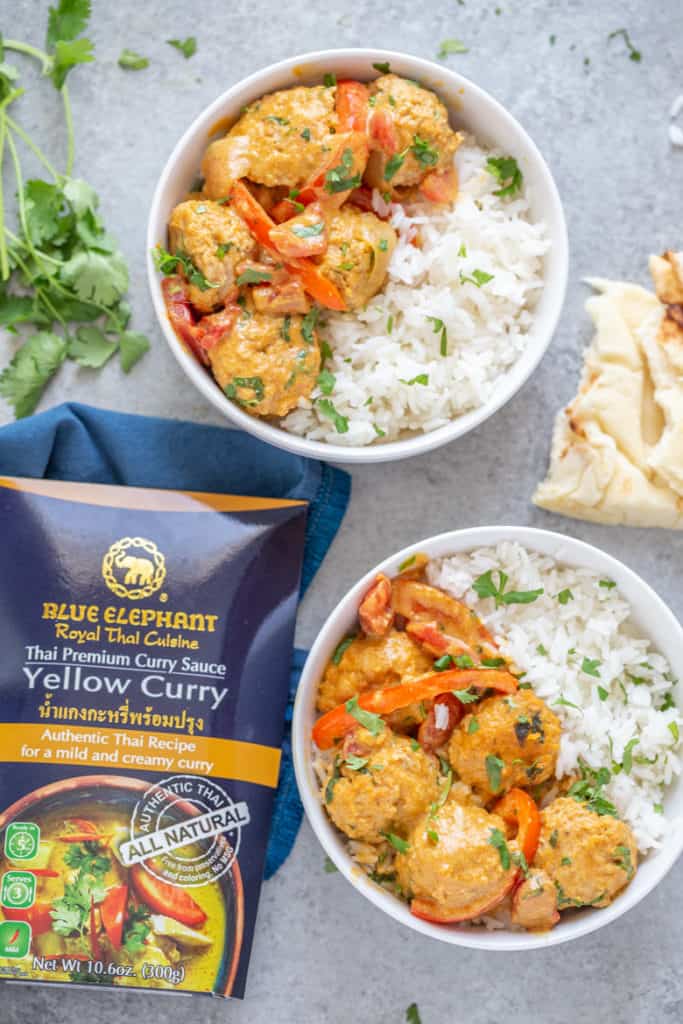 two bowls of chicken tikka masala meatballs with jasmine rice alongside Blue Elephant Yellow Curry Sauce