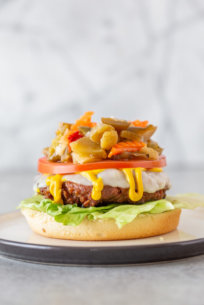 Beyond Meat Burgers are a plant-based patty piled high with provolone cheese, mustard, lettuce, tomato and giardiniera all on a seeded bun!