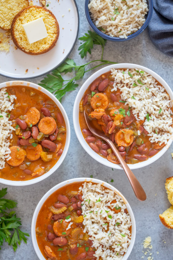 bowls full of red beans and topped with rice and a side of cornbread