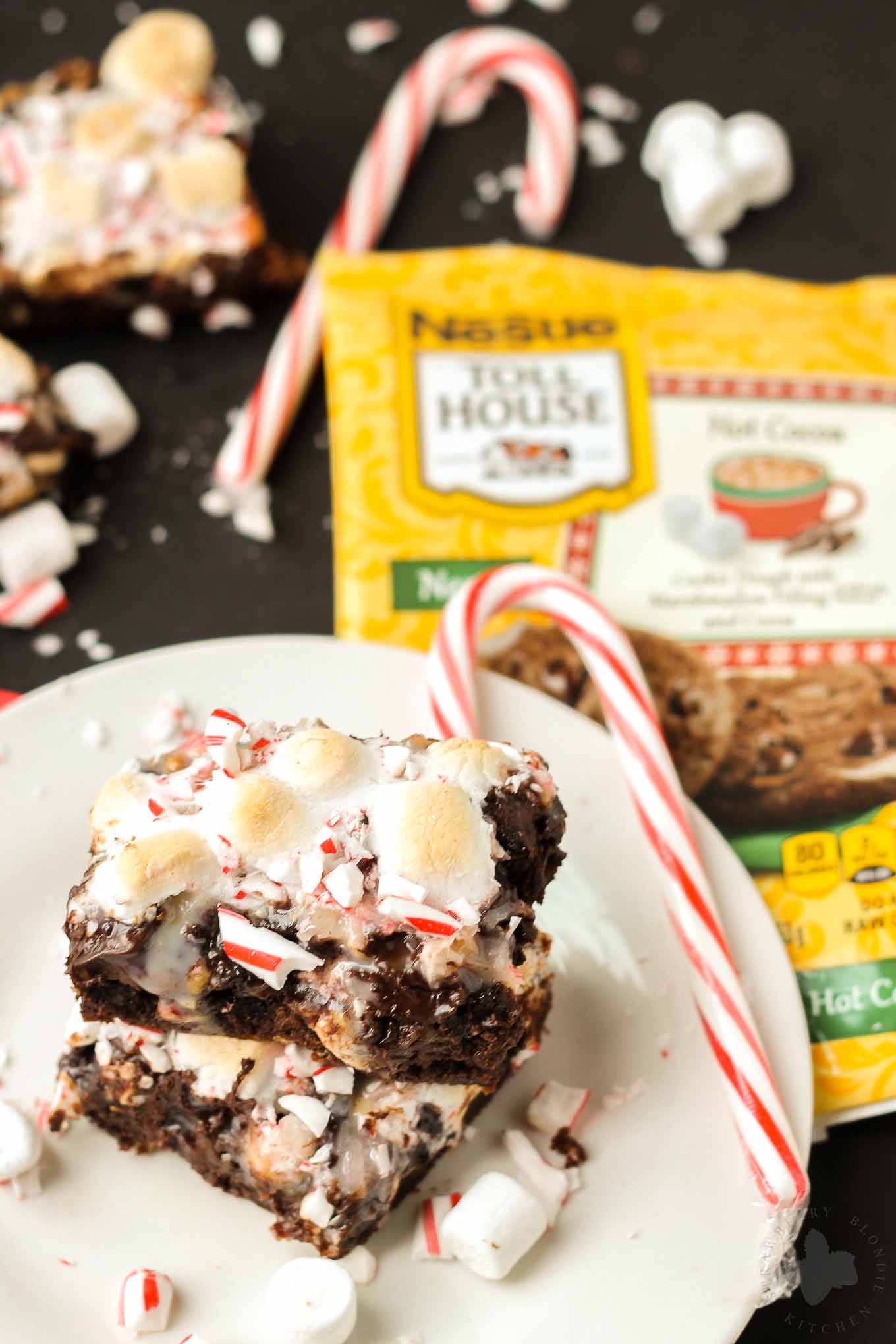 Have your hot cocoa and eat it too with these Peppermint Hot Cocoa Cookie Bars. They feature 7 layers of delicious cookies, chocolate, peanuts, coconuts, marshmallows and peppermint and then drizzled with sweetened condensed milk | Strawberry Blondie Kitchen