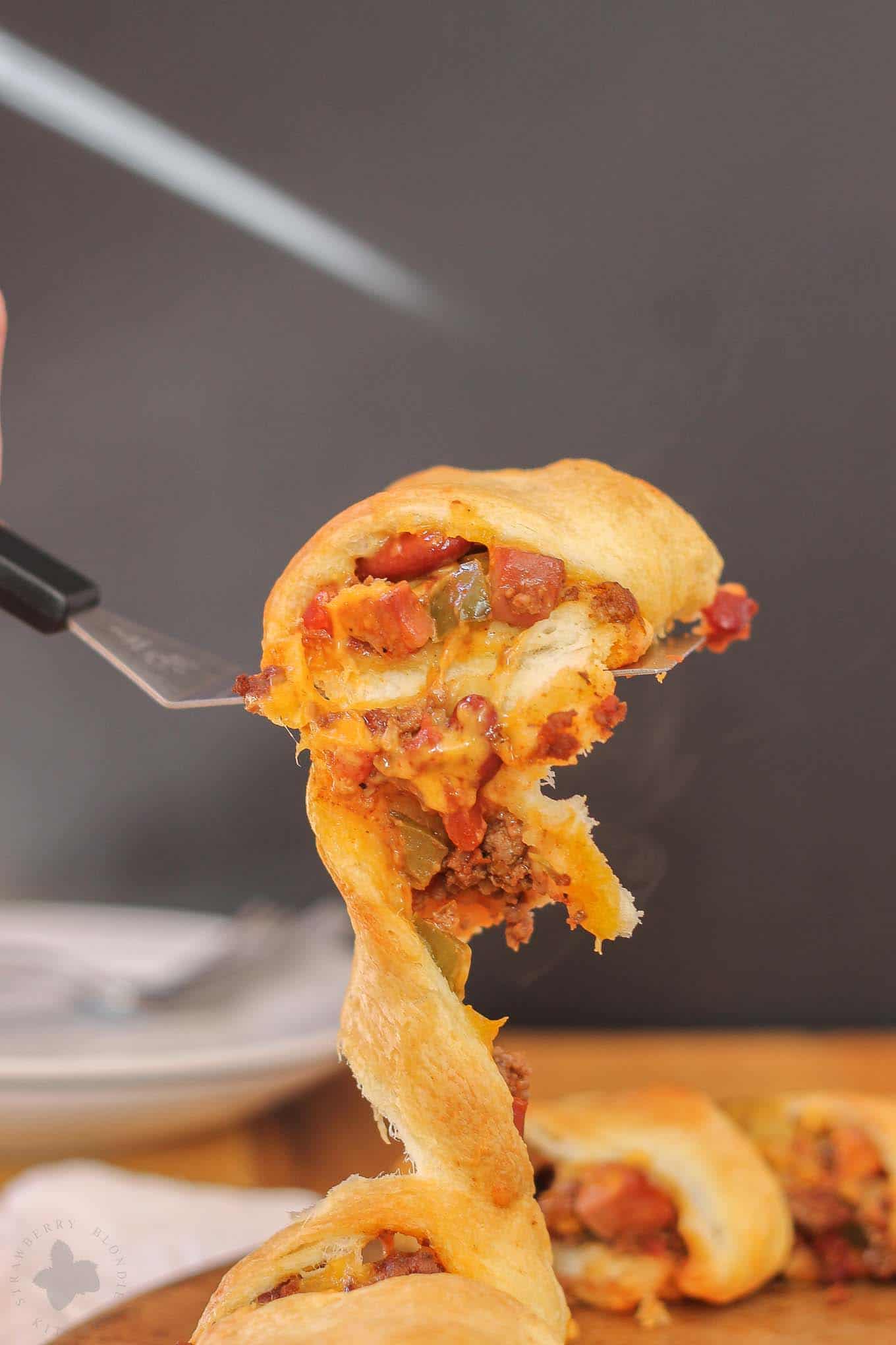 The flavors of an American classic, the chili cheese dog, have been rolled up into a crescent ring to bring you the ultimate game time food. You'll please even the pickiest of eaters with this Chili Cheese Dog Crescent Ring during dinnertime or any occasion. | Strawberry Blondie Kitchen