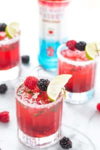 A hybrid between a mojito and a classic martini, this Triple Berry Mojitini is patriotism in a glass. Muddled mint, sugar and berries combine with limeade and Smirnoff Red White and Berry to bring you this refreshing cocktail perfect for all your outdoor parties! | Strawberry Blondie Kitchen