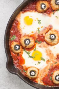 Eggs are baked in a tomato sauce and then breaded mushrooms with sliced black olives, made to looks like eyes, are nestled alongside to create Eyeballs in Purgatory. A festive Halloween meal sure to please the entire family! | Strawberry Blondie Kitchen