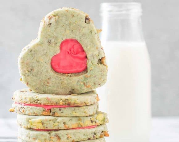 Your heart will grow three sizes with one bite of these Grinch Sandwich Cookies.  Pistachio shortbread cookies, with heart cutouts and red icing pay homage to one of childhood's favorite movies. | Strawberry Blondie Kitchen