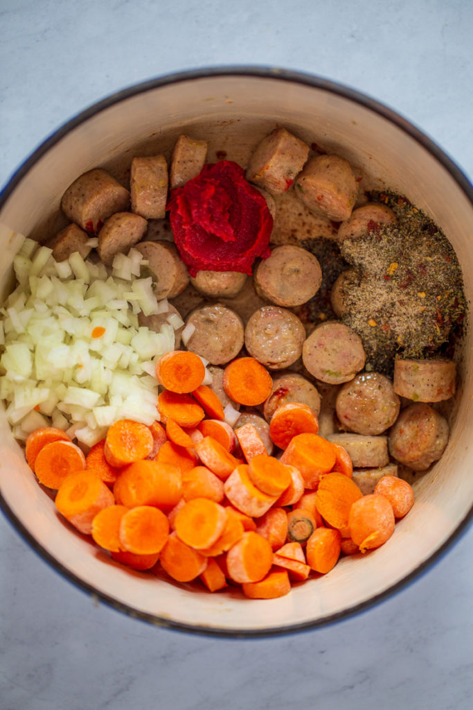 Italian chicken sausages cooking with onion, carrot, tomato paste and seasonings