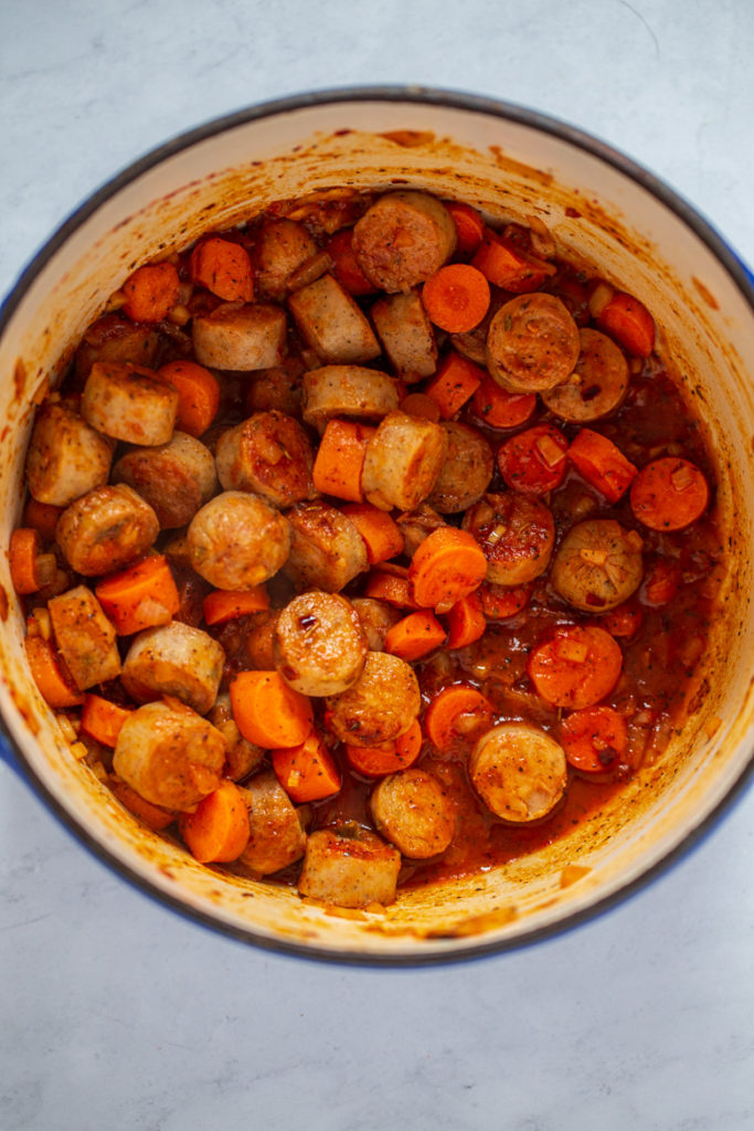 Italian chicken sausages cooking with onion, carrot, tomato paste, seasonings and chicken stock