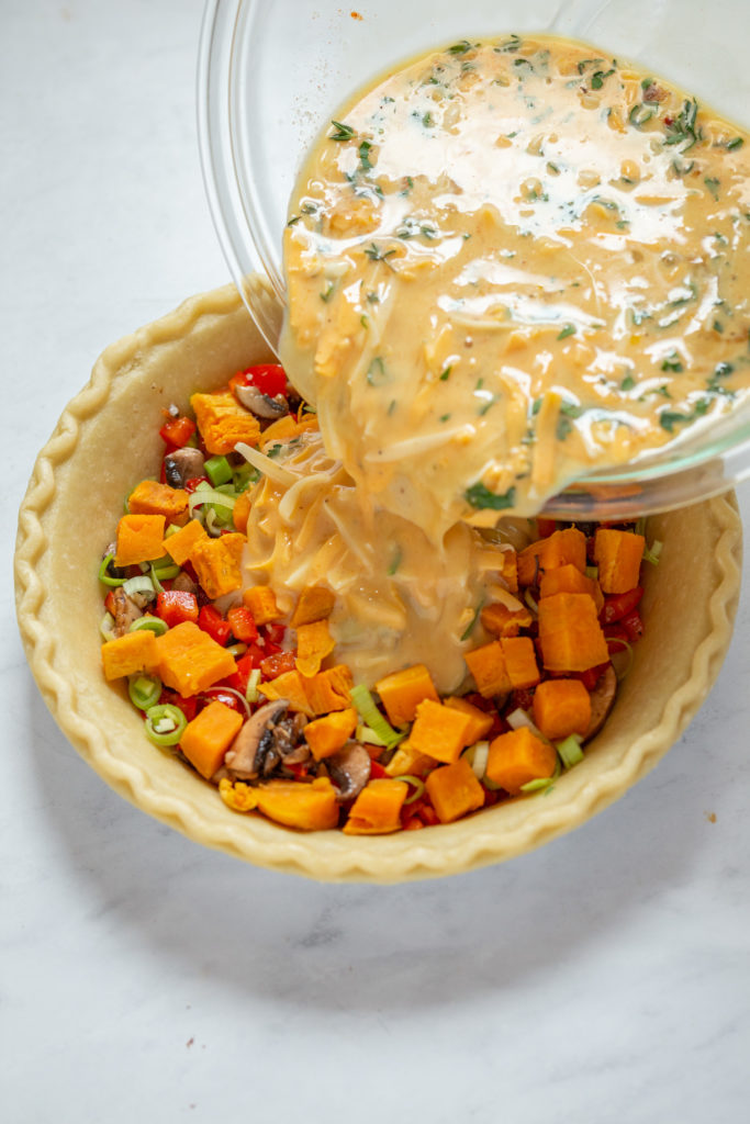 Pour the egg and milk mixture into the prepared pie crust with veggies to make this vegetable quiche